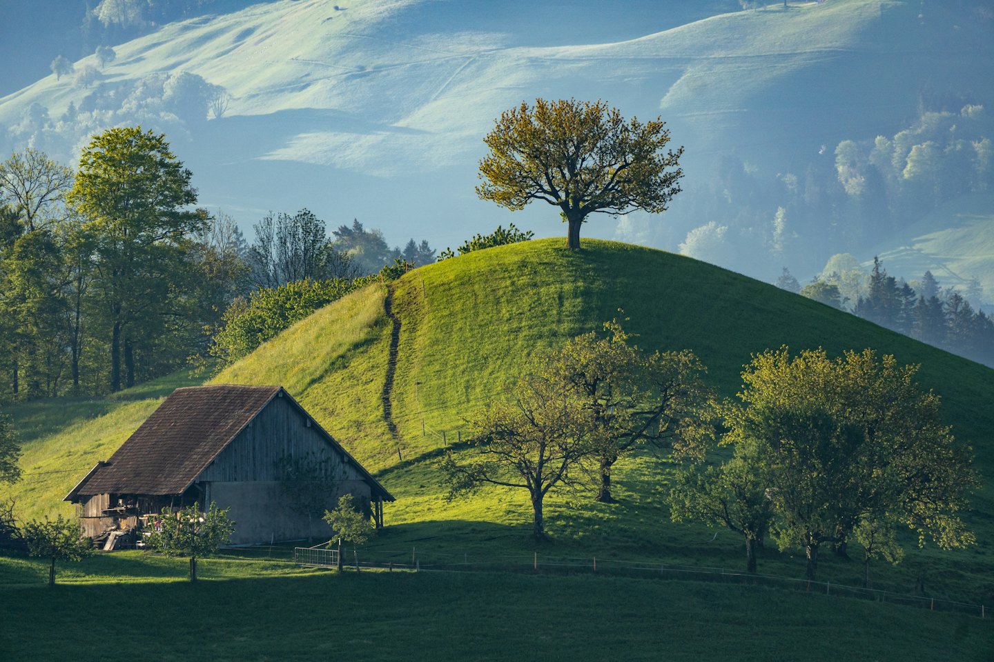 Un rustico fienile in legno si trova sotto dolci colline verdi.